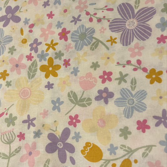 Close-up of Summer Bloom scrub cap fabric with purple, blue, pink, and yellow flowers on white cotton and fuchsia accents