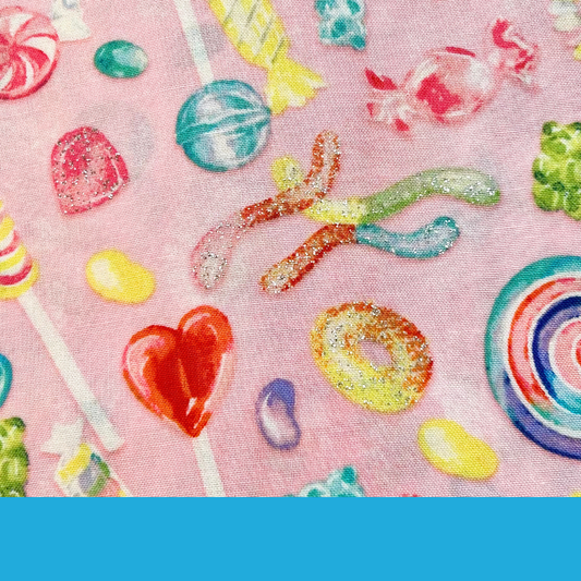 Close-up of Sugar Pop scrub cap fabric featuring colorful candy on a pink background with sky blue accents