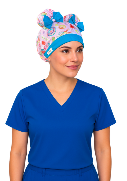 Nurse wearing Sugar Pop ScruBunz with two space buns, pink background, colorful candy design, and sky blue accents
